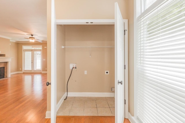 laundry area featuring hookup for an electric dryer, washer hookup, ceiling fan, crown molding, and a tile fireplace