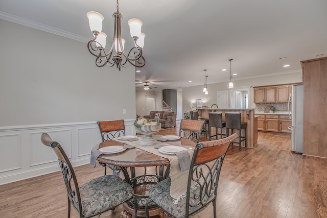 dining area featuring ceiling fan with notable chandelier, light hardwood / wood-style floors, and ornamental molding