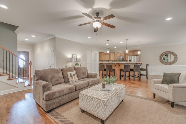 living room featuring light hardwood / wood-style floors, ceiling fan, and ornamental molding