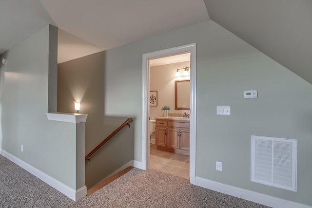 hall featuring light colored carpet, lofted ceiling, and sink