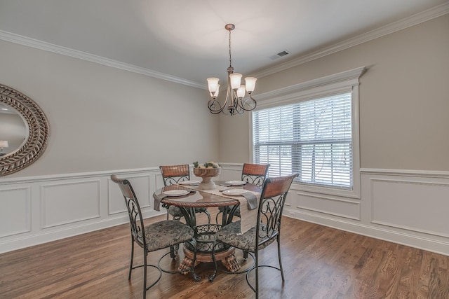 dining space with dark hardwood / wood-style floors, an inviting chandelier, and crown molding