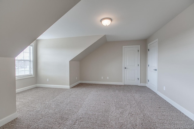 additional living space with light carpet and vaulted ceiling