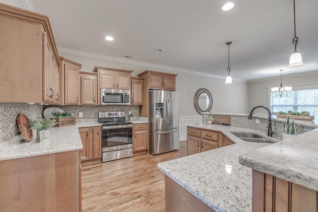 kitchen with an inviting chandelier, sink, hanging light fixtures, light stone counters, and stainless steel appliances