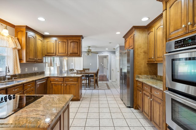 kitchen with light tile patterned flooring, appliances with stainless steel finishes, light stone countertops, and sink