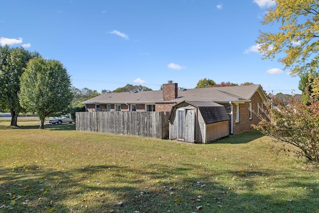 rear view of property featuring a yard and a storage shed