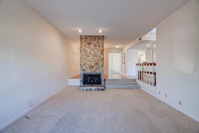 unfurnished living room featuring carpet and a stone fireplace