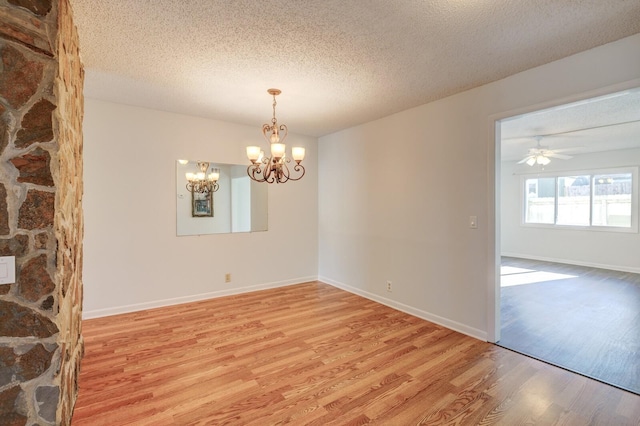 spare room with ceiling fan with notable chandelier, a textured ceiling, and hardwood / wood-style flooring