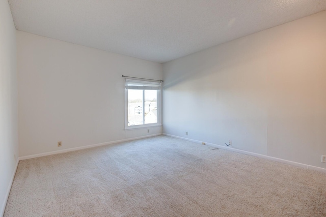 spare room with light colored carpet and a textured ceiling