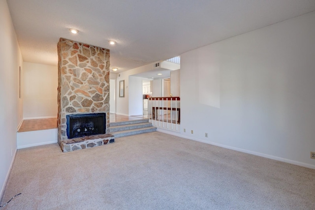 unfurnished living room featuring carpet and a stone fireplace