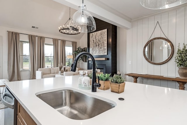 kitchen featuring dishwasher, sink, an inviting chandelier, decorative light fixtures, and wooden walls