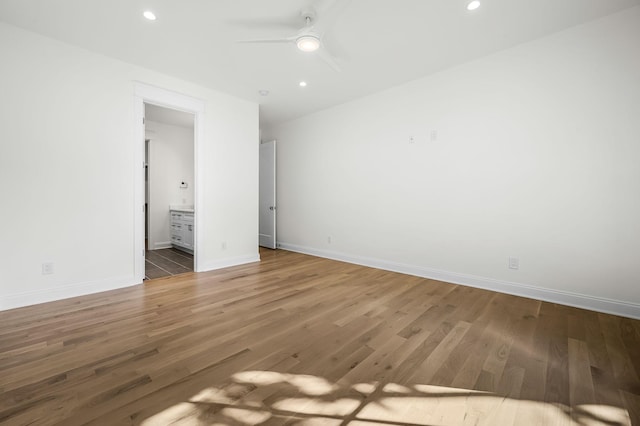 unfurnished bedroom featuring ensuite bath, ceiling fan, and hardwood / wood-style flooring