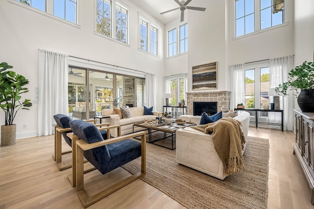 living room with light hardwood / wood-style flooring, a high ceiling, and a tiled fireplace