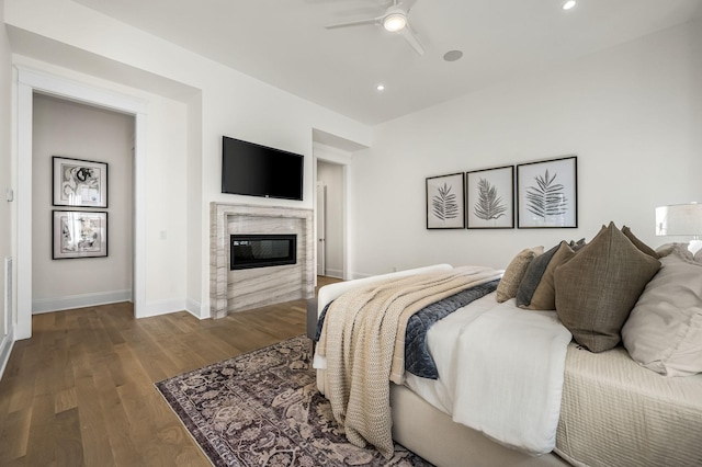 bedroom with hardwood / wood-style floors, ceiling fan, and a premium fireplace