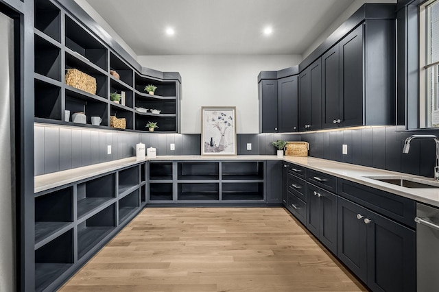 interior space with backsplash, dishwasher, sink, and light hardwood / wood-style flooring