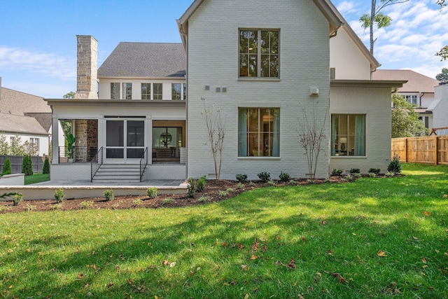 back of property with a sunroom, a patio, and a lawn