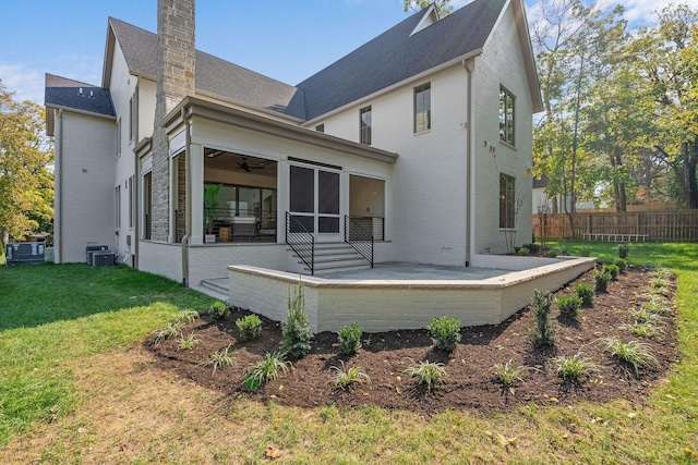 rear view of property with a lawn, a sunroom, central air condition unit, and a patio