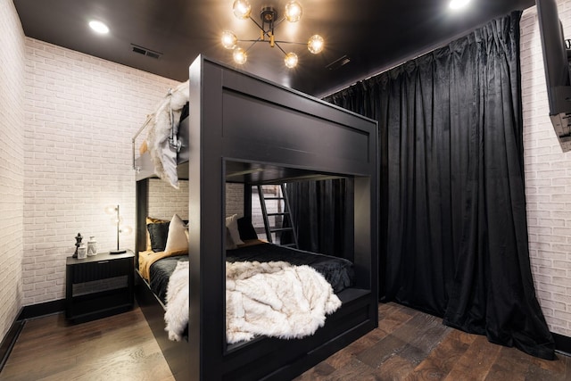 bedroom with brick wall and dark hardwood / wood-style flooring