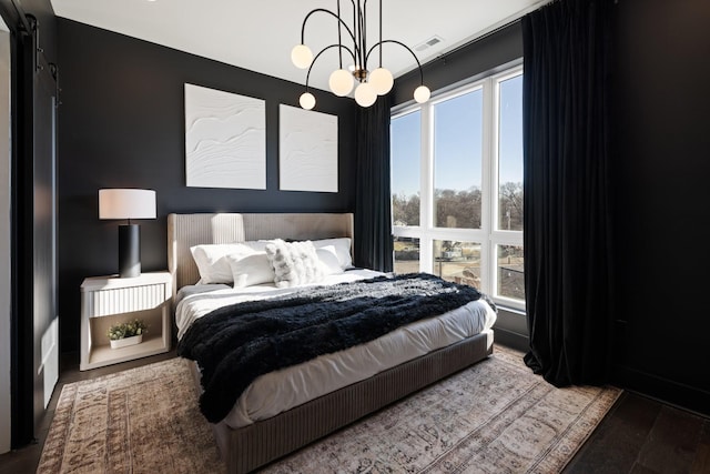 bedroom featuring a chandelier, wood-type flooring, and multiple windows