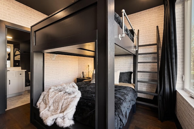 bedroom featuring brick wall and dark hardwood / wood-style flooring