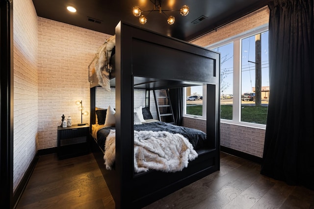 bedroom featuring dark wood-type flooring and brick wall