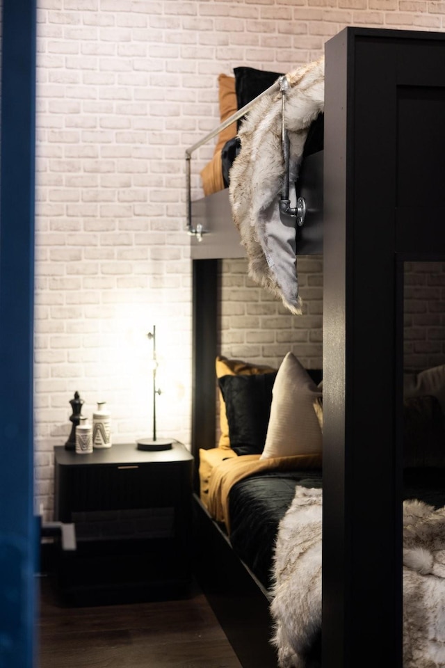 bedroom with brick wall and hardwood / wood-style floors