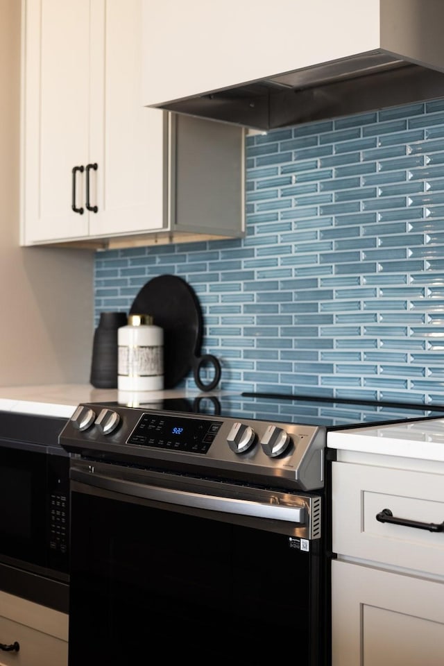 kitchen with white cabinets, backsplash, wall chimney range hood, and stainless steel range with electric stovetop