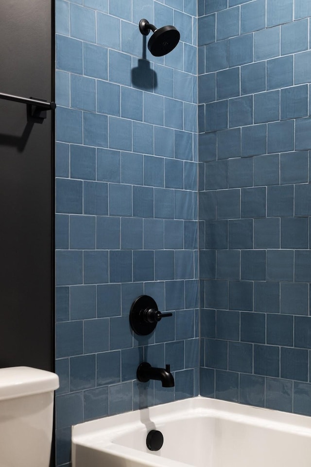 bathroom featuring tiled shower / bath combo and toilet