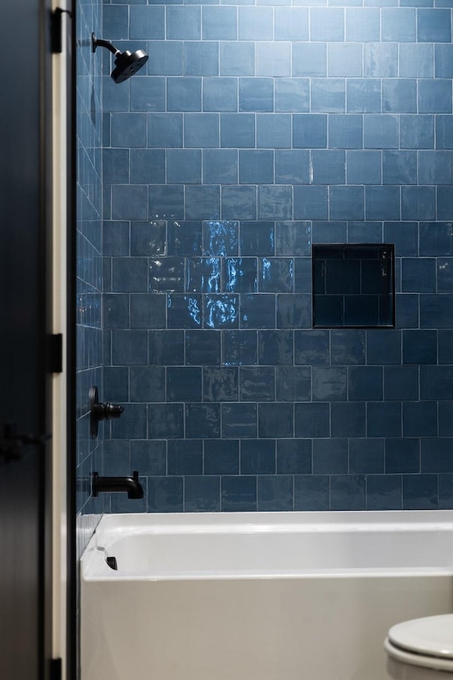 bathroom featuring toilet and tiled shower / bath combo