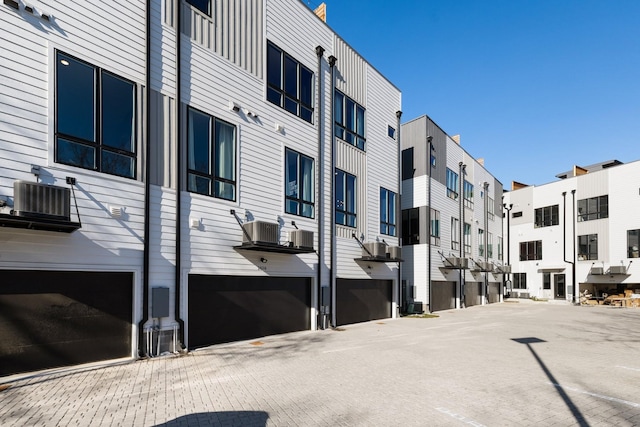 view of building exterior featuring central AC unit and a garage