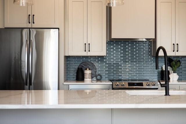 kitchen featuring decorative backsplash, range, stainless steel fridge, and light stone countertops