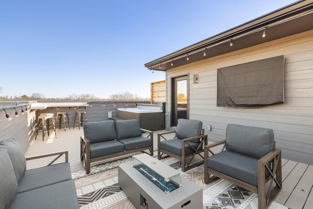 deck with a hot tub, a bar, and an outdoor living space with a fire pit