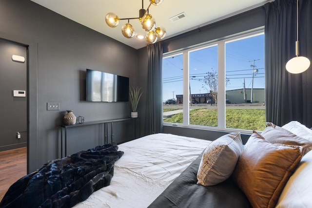 bedroom with wood-type flooring and an inviting chandelier