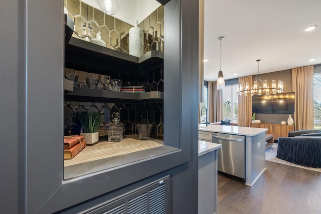 bar featuring dark wood-type flooring, sink, hanging light fixtures, a chandelier, and stainless steel dishwasher