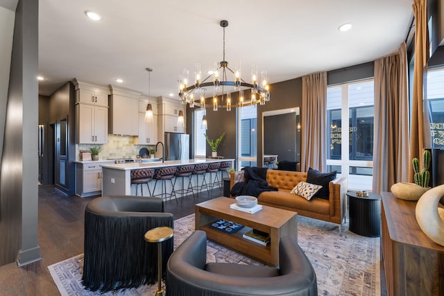 living room featuring a notable chandelier, dark wood-type flooring, and sink