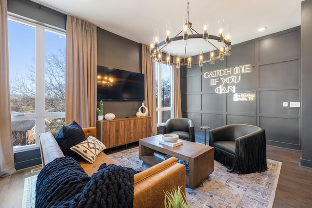 living room featuring wood-type flooring, a wealth of natural light, and an inviting chandelier