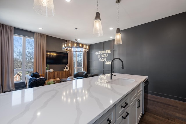 kitchen featuring dark hardwood / wood-style floors, sink, hanging light fixtures, light stone counters, and dishwashing machine