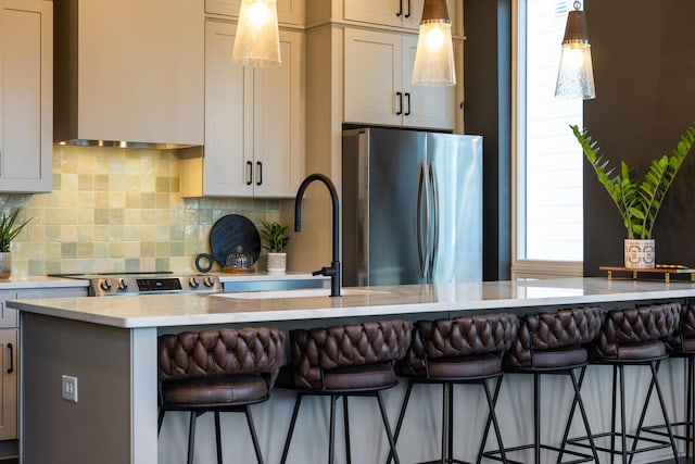 kitchen with tasteful backsplash, stainless steel refrigerator, a kitchen island, pendant lighting, and a breakfast bar