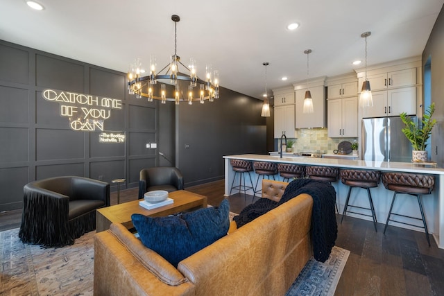 living room with dark hardwood / wood-style flooring, sink, and a notable chandelier