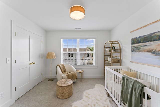 bedroom with light colored carpet and a nursery area