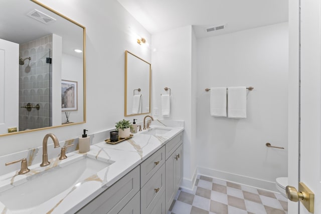 bathroom with a tile shower, vanity, and toilet