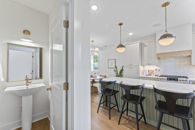 kitchen with white cabinets, decorative backsplash, a kitchen bar, and high end stainless steel range oven