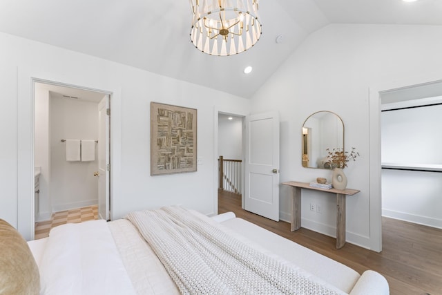 bedroom with wood-type flooring, an inviting chandelier, vaulted ceiling, and ensuite bathroom