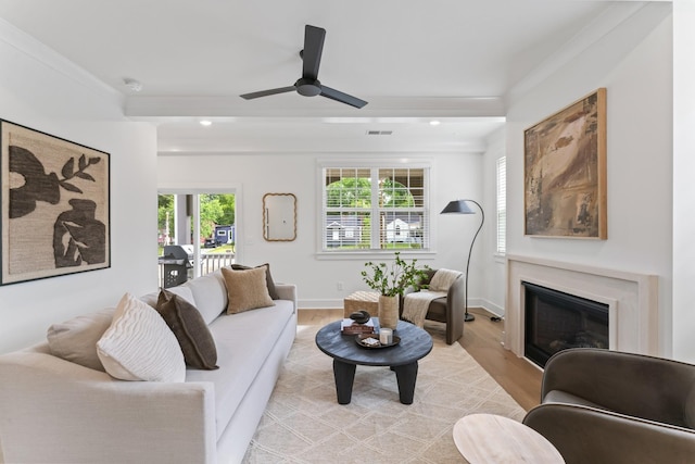 living room with ceiling fan, a healthy amount of sunlight, ornamental molding, and light hardwood / wood-style flooring