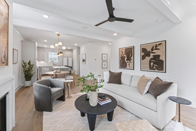 living room with ceiling fan, light hardwood / wood-style flooring, beamed ceiling, and ornamental molding