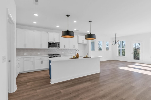 kitchen with dark hardwood / wood-style flooring, decorative light fixtures, a center island with sink, white cabinets, and a chandelier