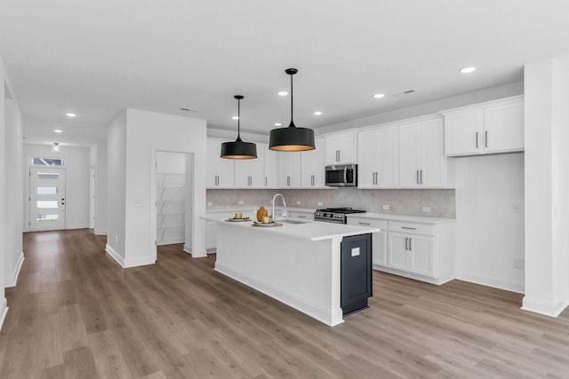 kitchen featuring stainless steel appliances, white cabinetry, and a center island with sink