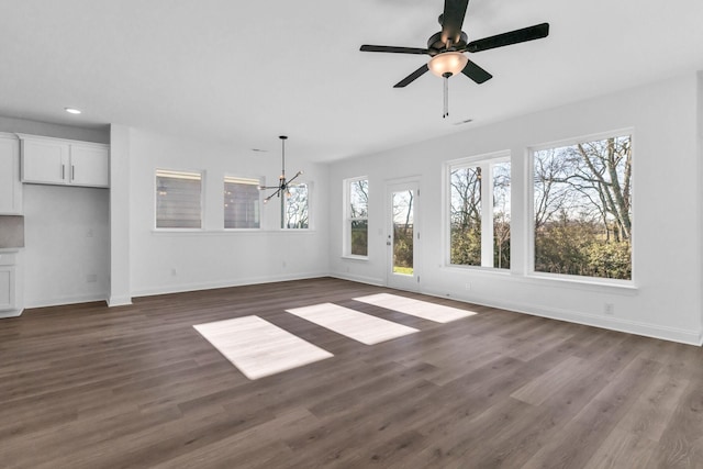 unfurnished living room featuring ceiling fan with notable chandelier and dark hardwood / wood-style floors