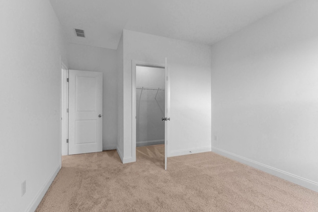 unfurnished bedroom featuring light colored carpet, a spacious closet, and a closet