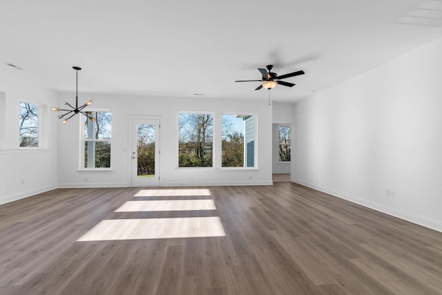 unfurnished living room featuring ceiling fan with notable chandelier and hardwood / wood-style flooring