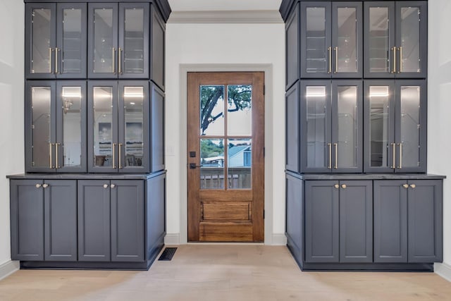 doorway to outside featuring crown molding and light hardwood / wood-style floors